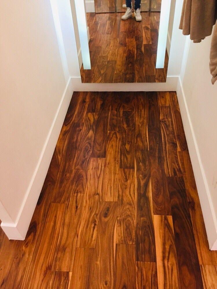Hallway with polished wooden flooring and a large mirror at the end reflecting a person's feet.