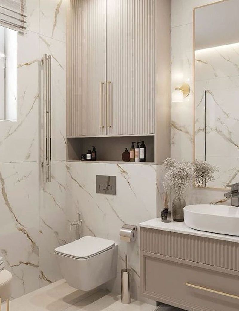 Modern bathroom with marble walls, floating toilet, vanity with sink, and decorative items.